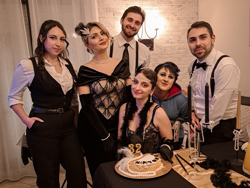 Ospiti in abiti anni ’20 intorno a una torta di compleanno